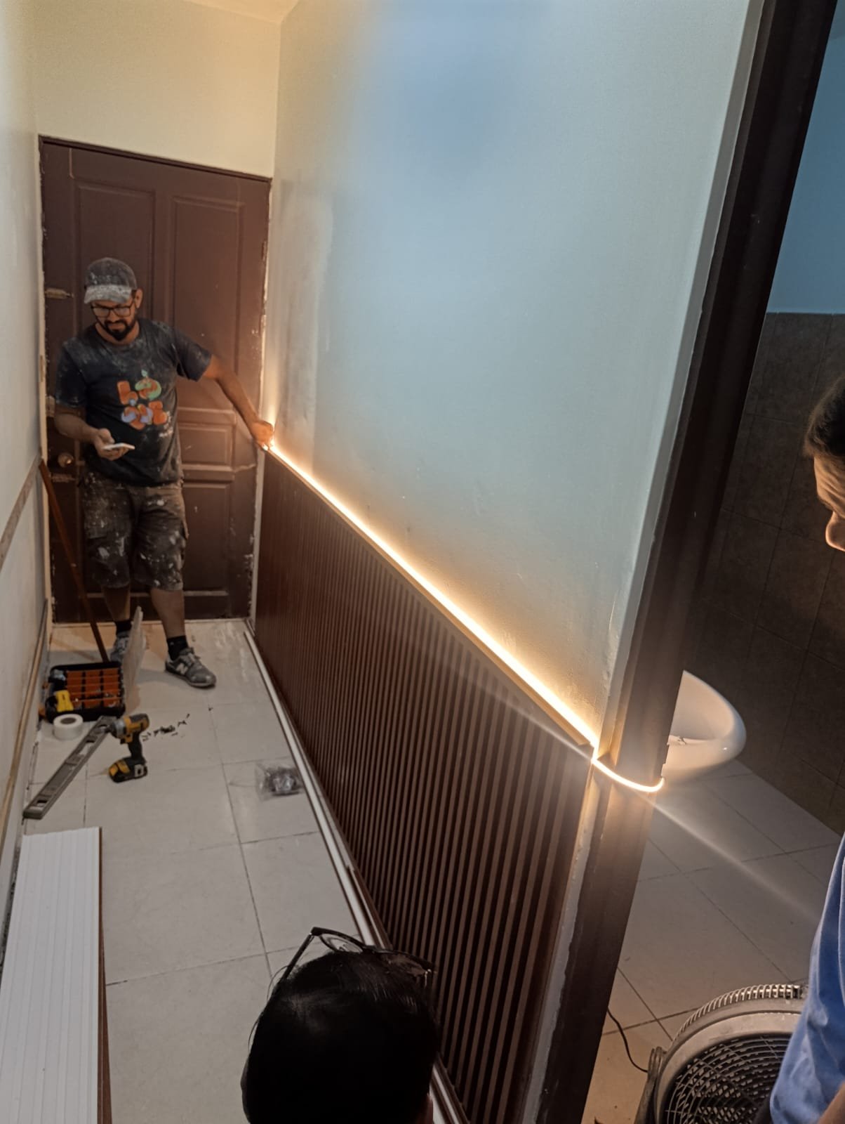 Técnico instalando iluminación LED y paneles de acabado en un pasillo remodelado